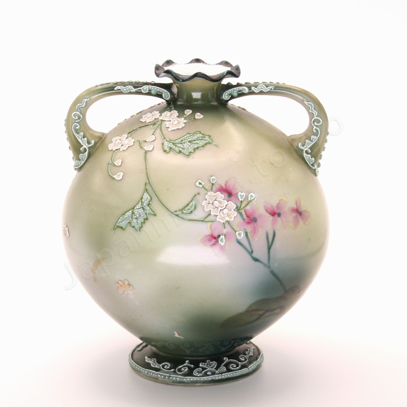 Back view: Japanese old fine china. Old Noritake.
This exquisite and captivating piece showcases polychrome and Moriage decoration, featuring delicate white flowers tinged with soft pink and leaves outlined in green. The upper and lower portions are finished in a smoky green, while the center glows with a radiant brightness, as though illuminated by light. The elegantly small mouth of the base, complemented by graceful handles on both sides, adds to its charm and timeless appeal.