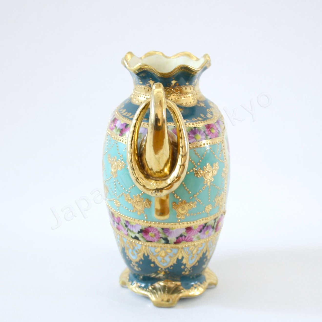 Side view: Japanese antique fine china, Old Noritake.
Vase, featuring rose motifs and gold relief detailing, with pretzel-shaped handles adding a unique touch.