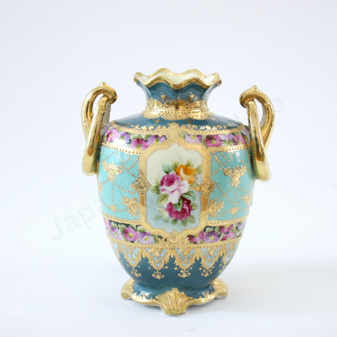 Back view: Japanese antique fine china, Old Noritake.
Vase, featuring rose motifs and gold relief detailing, with pretzel-shaped handles adding a unique touch.