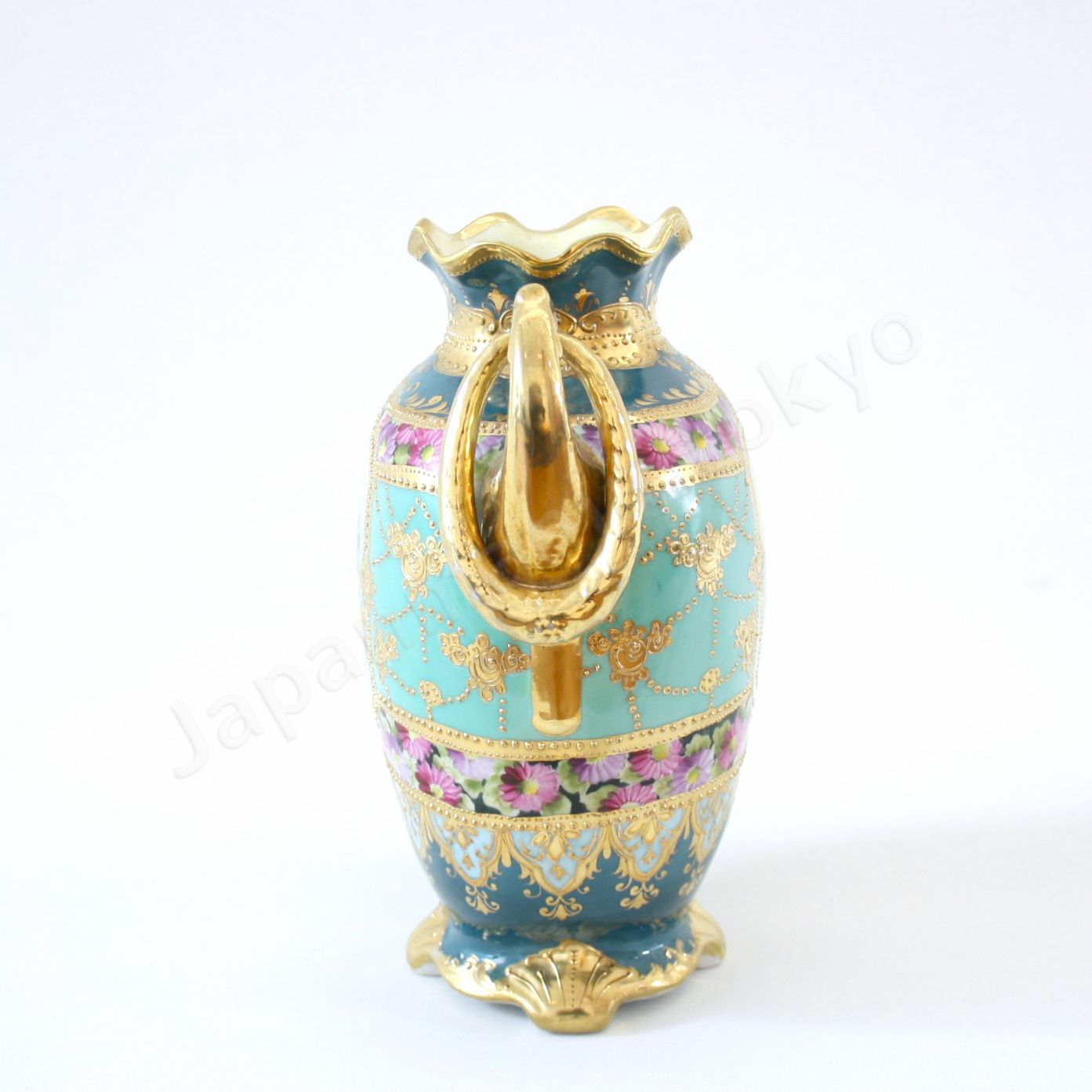 Side view: Japanese antique fine china, Old Noritake.
Vase, featuring rose motifs and gold relief detailing, with pretzel-shaped handles adding a unique touch.