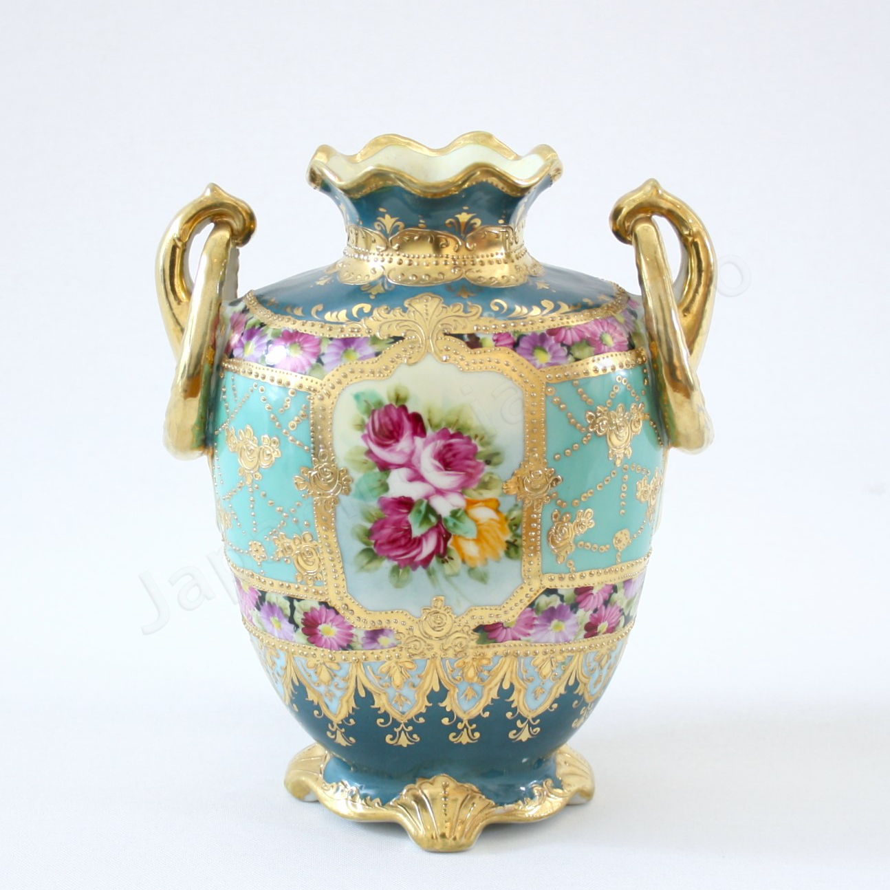 Front view: Japanese antique fine china, Old Noritake.
Vase, featuring rose motifs and gold relief detailing, with pretzel-shaped handles adding a unique touch.